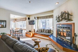 Una sala de estar con sofá, mesa de centro, chimenea y televisor.