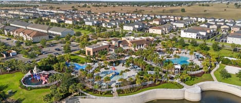 Vista aérea de una zona residencial con una piscina central, rodeada de casas y vegetación.