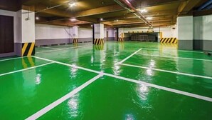 Eine überdachte Parkgarage mit grünem Boden und weißen Linien, die die Parkplätze abgrenzen.