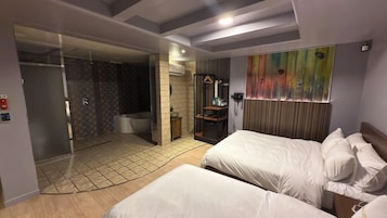 Habitación de hotel con dos camas, zona de ducha y baño.