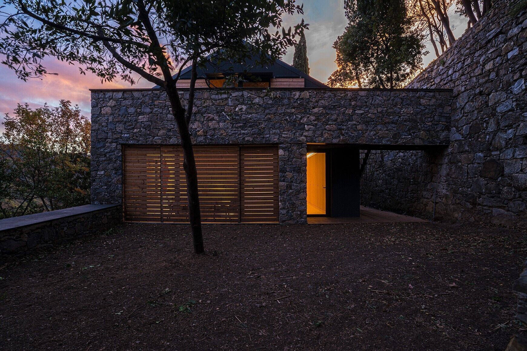 Un bâtiment en pierre doté d’un grand portail de garage et d’une entrée ouverte.