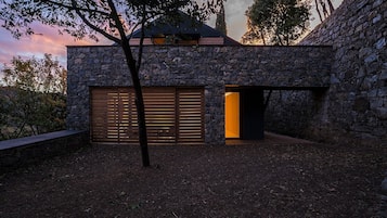 Un bâtiment en pierre doté d’un grand portail de garage et d’une entrée ouverte.