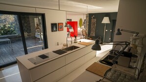 A modern kitchen with a large island, a dining area with a red chair, and a view of a patio.