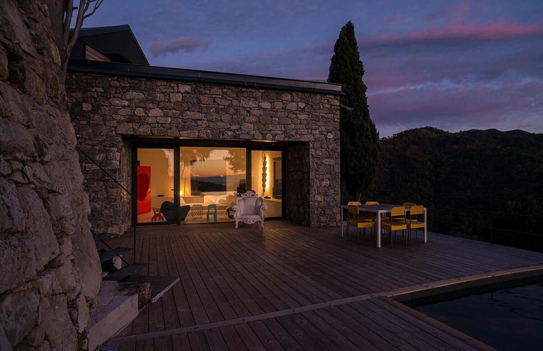 A stone building with a wooden deck and a pool.