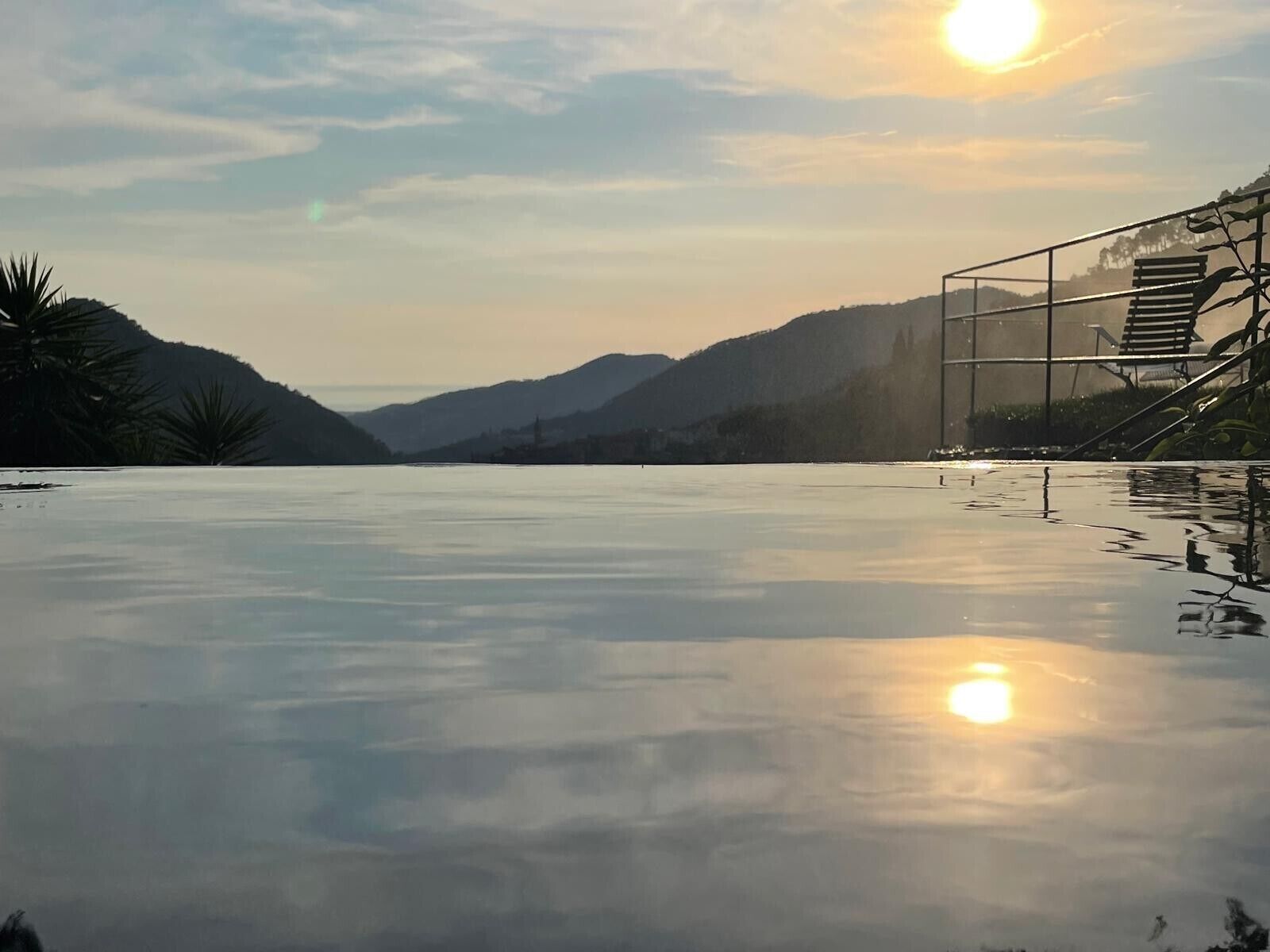 Un espace piscine extérieur paisible, offrant une vue dégagée sur les collines environnantes et un magnifique coucher de soleil en arrière-plan.