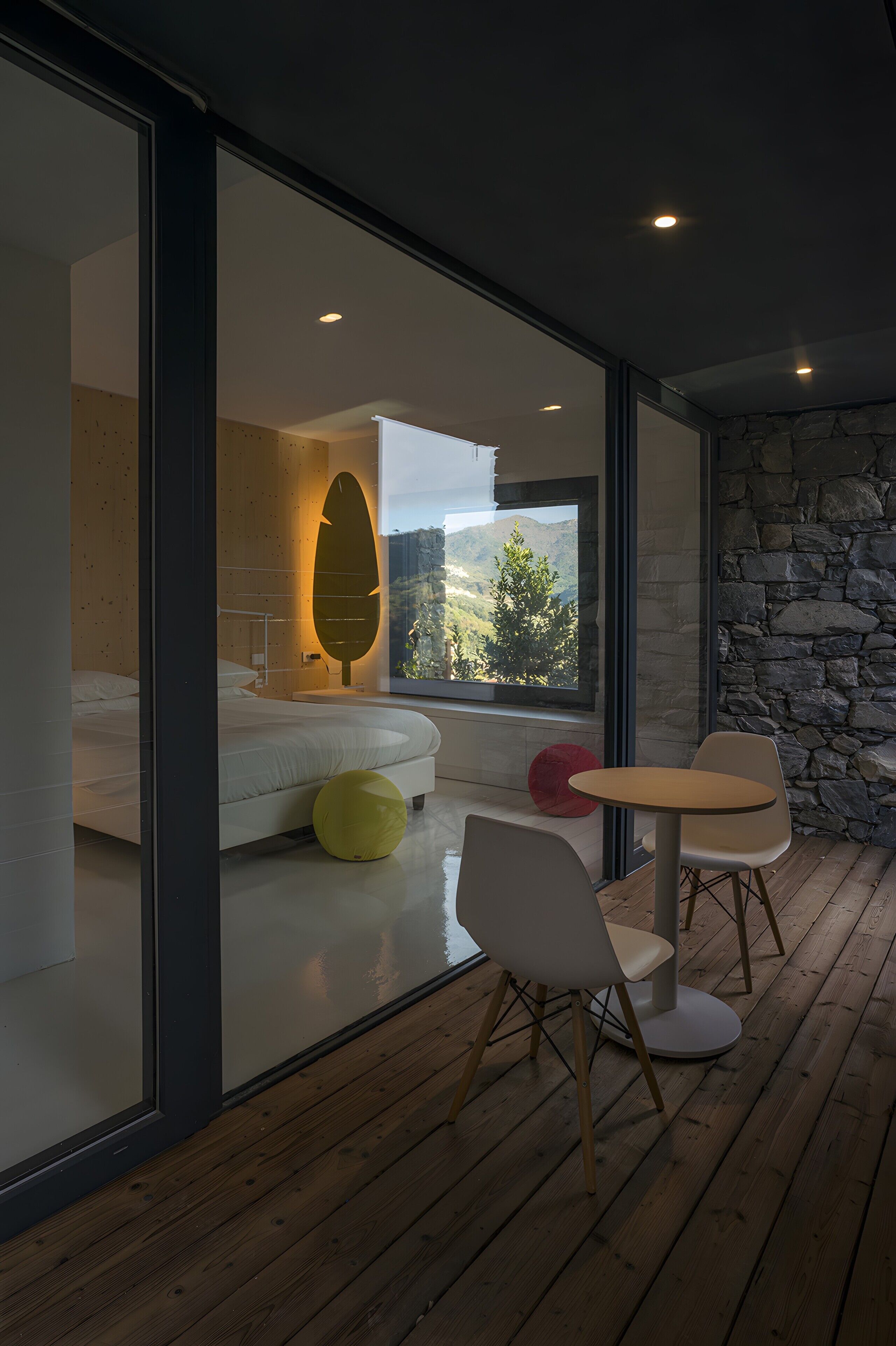 Une chambre moderne avec un grand lit, un mur en verre et une vue sur un paysage montagneux.