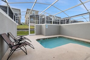 Un espace piscine doté d’une enceinte en verre, de chaises longues et offrant une vue dégagée sur les bâtiments environnants.