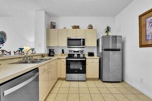 A compact kitchen with a dishwasher, microwave, oven, and refrigerator. - Last Minute Disney Getaway! Townhouse with Private Pool. Book Now! #107933 (Orlando)