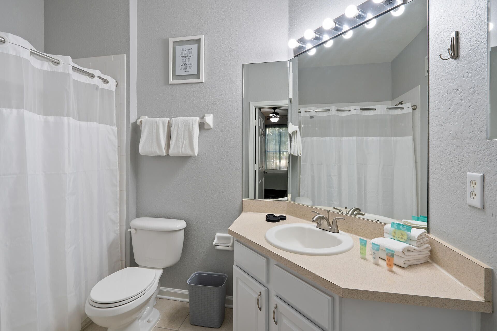 A bathroom with a toilet, sink, and mirror.