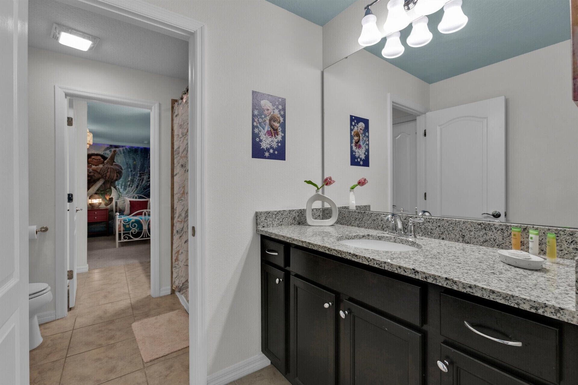 A bathroom with a double sink vanity, dark cabinets, and a large mirror.