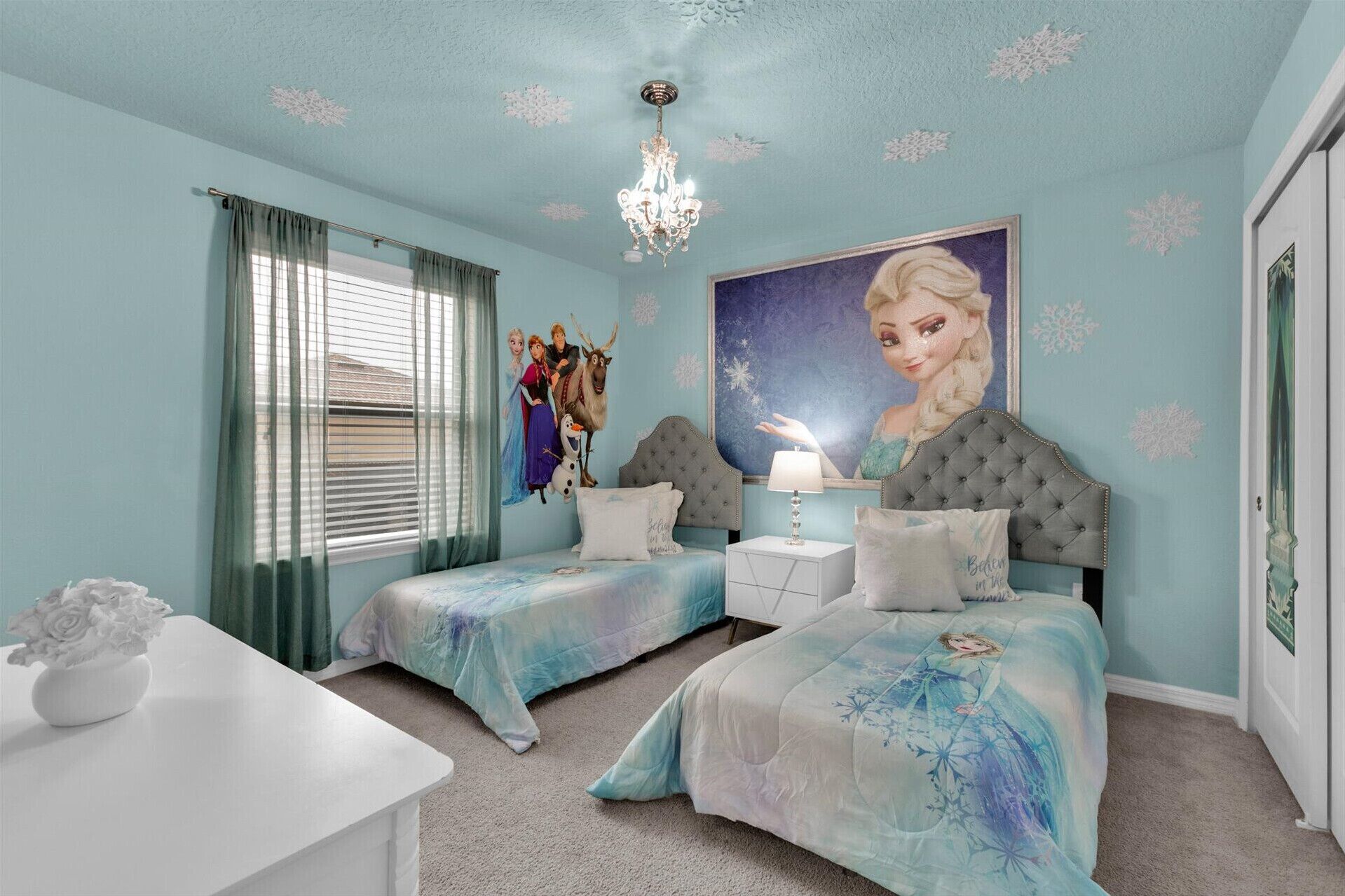 A bedroom with two beds, a chandelier, and a large poster of a character.