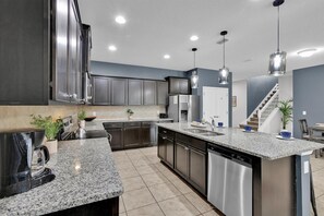 A modern kitchen with granite countertops, stainless steel appliances, and pendant lighting. - Last Minute Disney! Private Pool, Game Room & Themed Bedrooms. Book Now! #108401 (Orlando)