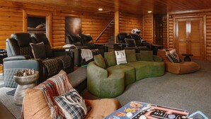 Ein Holzblockhaus-Interieur mit einem Wohnbereich, ausgestattet mit Sofas, einem Massagesessel und einem Schachbrett.