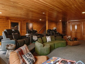 A log cabin interior with a living area featuring sofas, a massage chair, and a chessboard. - Fall Smokies Retreat: Theater, Fireplaces & Hot Tub Across 4 Levels (Sevierville)