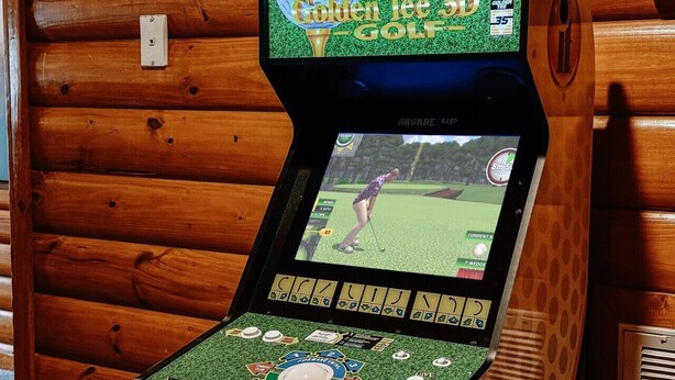 Eine Spielekonsole für Golfspiele mit Bildschirm, der ein Golfturnier zeigt, umgeben von Holzverkleidung.