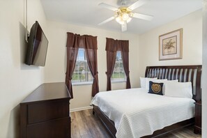 A bedroom with a bed, a ceiling fan, a TV mounted on the wall, and a window with curtains. - Windsor Palms 75 - Four Bedroom Villa, Sleeps 10 (Orlando)