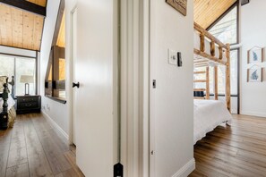 Ein Schlafzimmer mit einem Bett, Holzboden, einem Fenster und einer Tür.