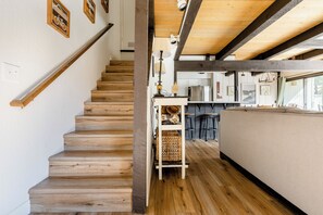 A wooden staircase leading to a kitchen area with a bar and seating. - Premier Townhouse, Closest to the Slopes (Big Bear Lake)