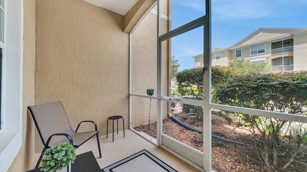 Ein Balkon mit einem Stuhl, einem kleinen Hocker und einem Blumentopf.