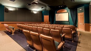 Um teatro com fileiras de assentos, uma tela e uma porta.