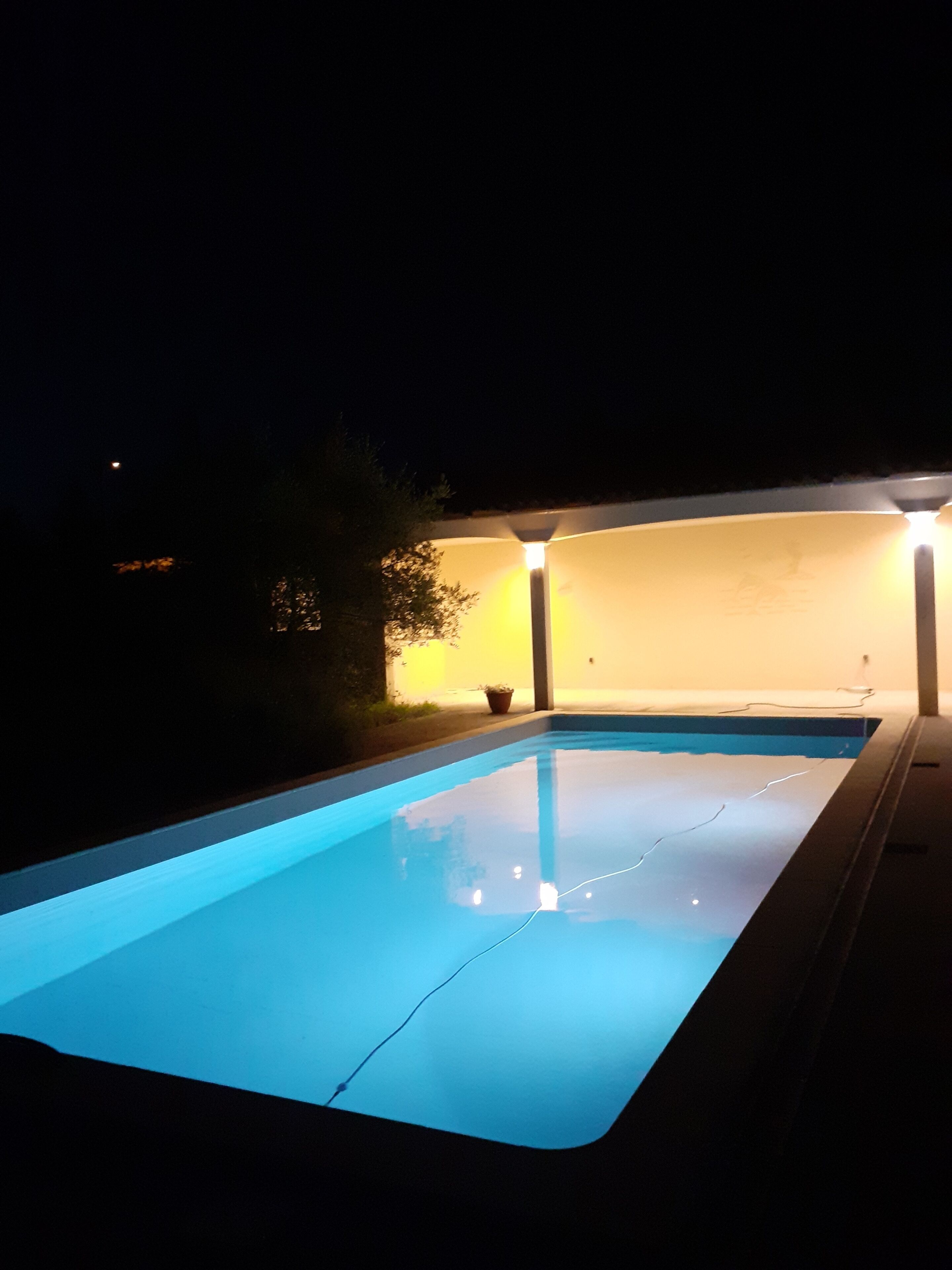 Une piscine la nuit, avec des bords illuminés.