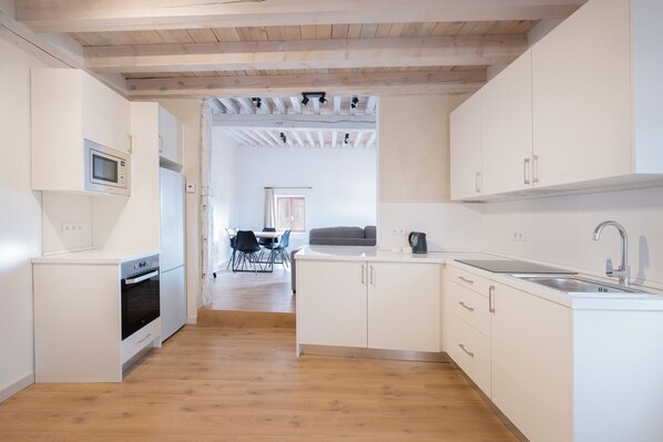 A modern kitchen with white cabinetry, a built-in oven, a microwave, and a sink.