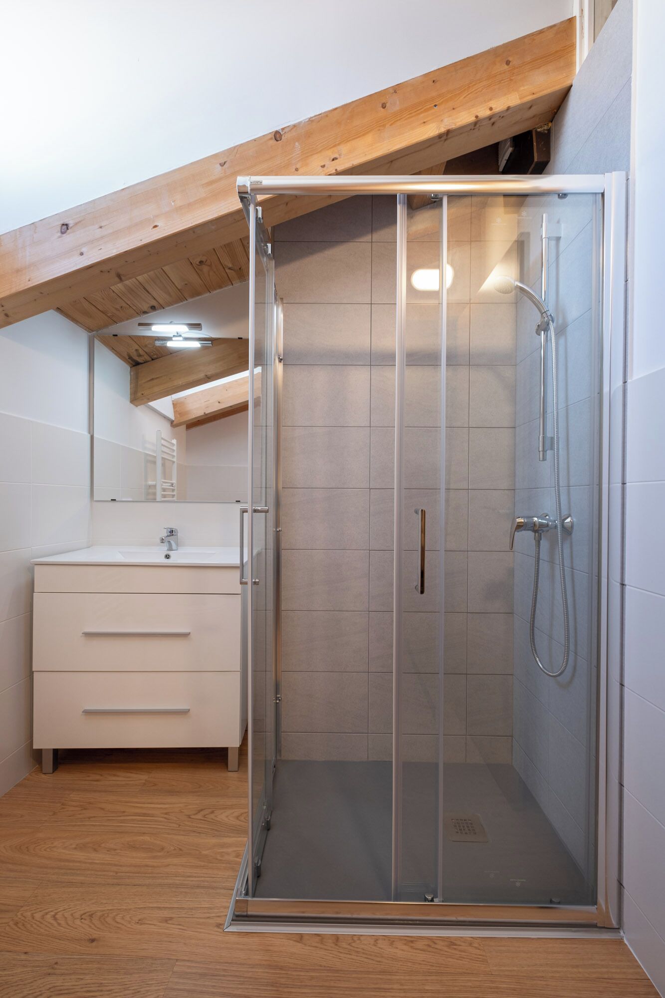 Une salle de bain moderne avec une douche à parois de verre, un plafond en bois et un meuble-lavabo blanc.