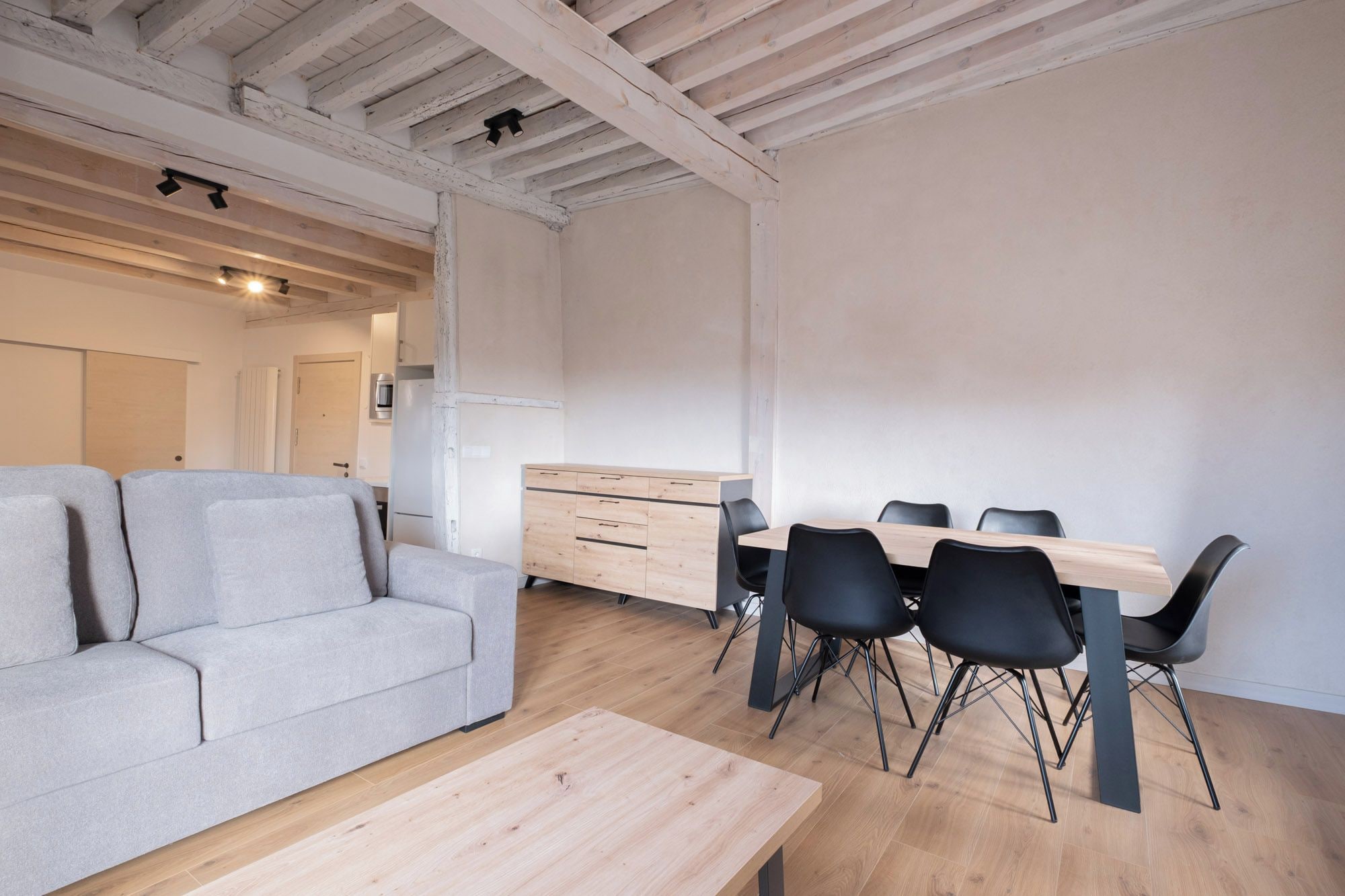 Un interno moderno con divano, tavolo da pranzo, sedie e angolo cottura.