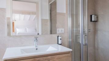 A bathroom with a white sink, wooden vanity, a glass shower enclosure, and a mirror above the sink.