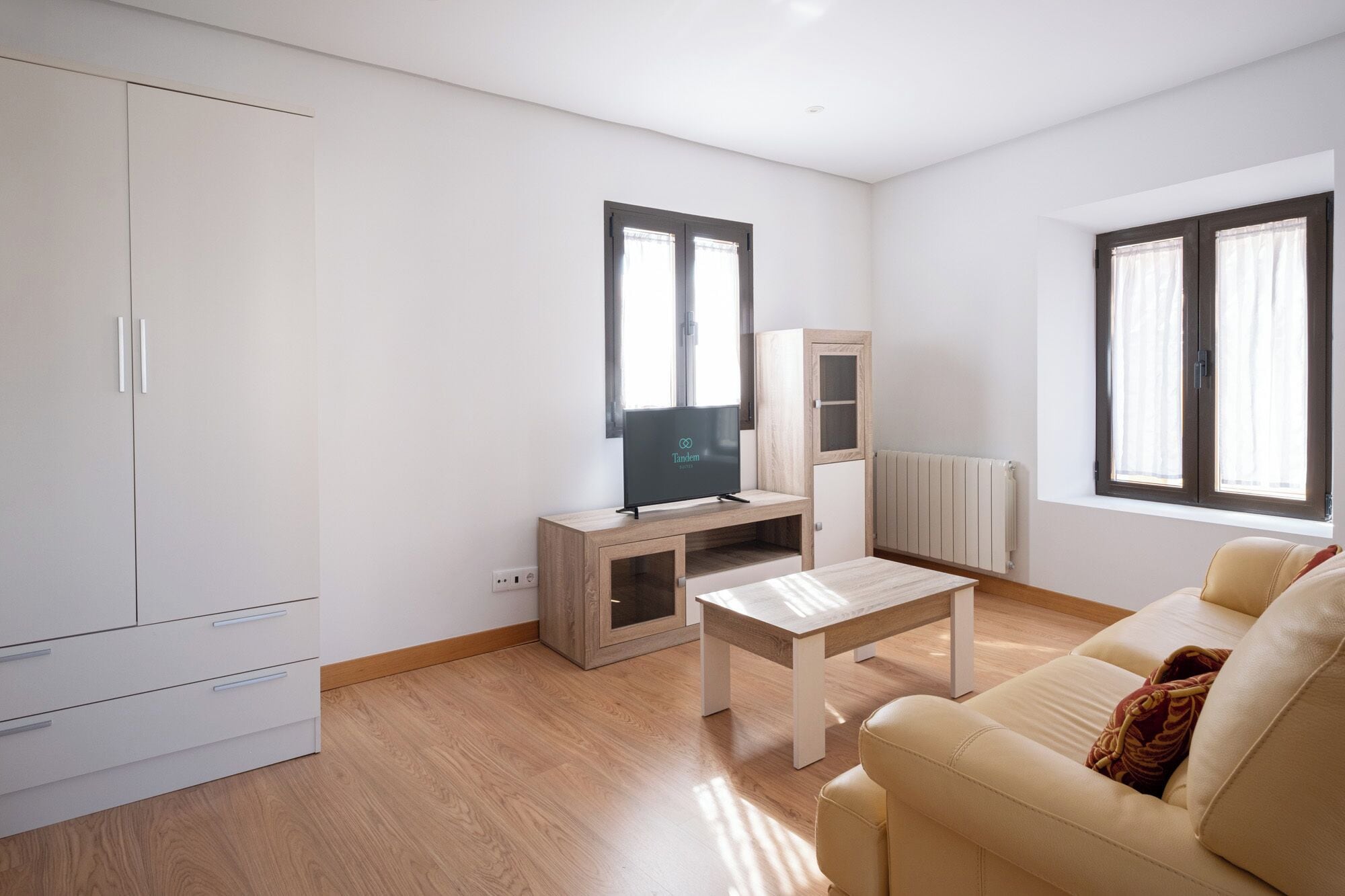 A modern living room with a sofa, a coffee table, a TV on a stand, and a cabinet.