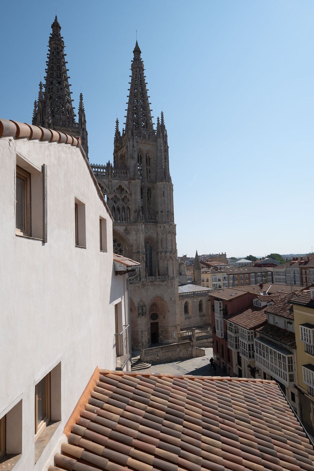 A cathedral with two spires, a white building with a tiled roof, and a cityscape in the background.