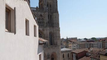 A cathedral with two spires, a white building with a tiled roof, and a cityscape in the background.