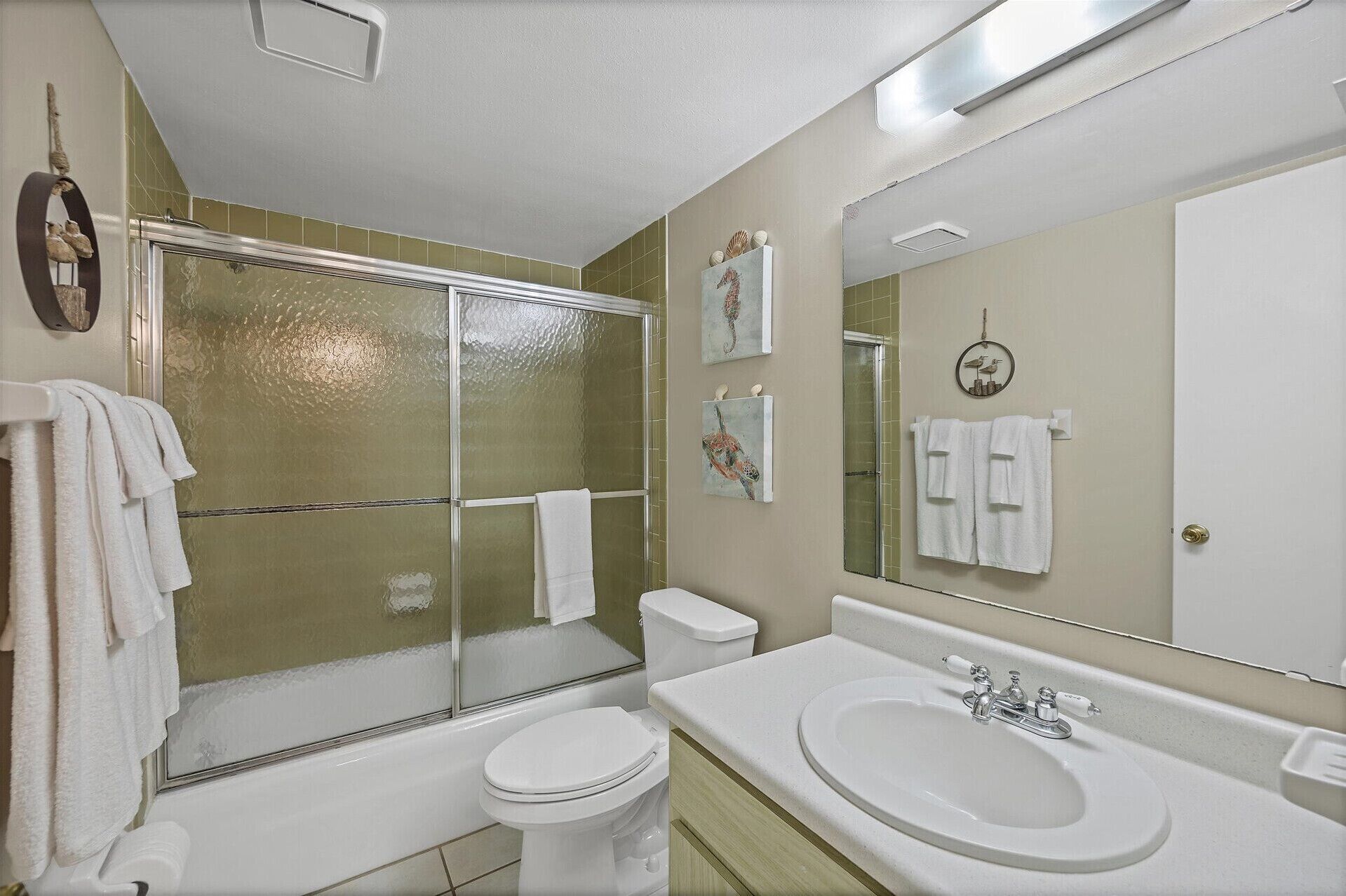 A bathroom with a glass-enclosed shower, a toilet, a sink, and a mirror.