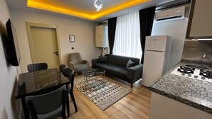 Un espace de vie compact comprenant un coin repas, un canapé et une kitchenette.
