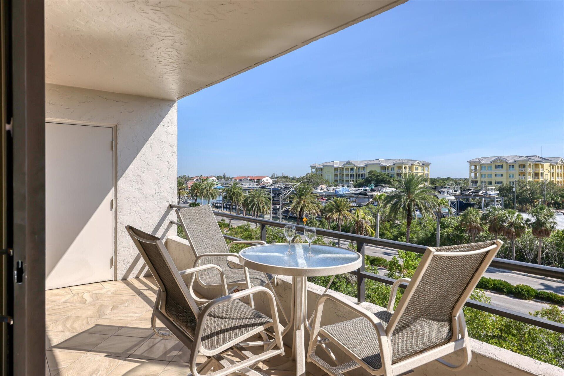 A balcony with a table and chairs, overlooking a marina with boats and buildings.