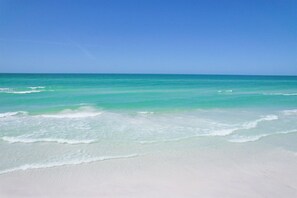 Ein Strand mit klarem türkisblauem Wasser und weißem Sand.