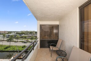 A balcony with a view of a marina and buildings, a chair, and a small table. - Siesta Key 236 - Two Bedroom Apartment, Sleeps 6 (Siesta Key)