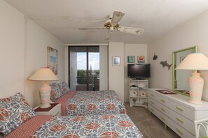 Ein Schlafzimmer mit einem Bett, einem Fernseher, einem Schminktisch und einem Deckenventilator.