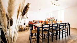 A dining area with a wooden table and chairs, a chandelier, and a window with natural light. - "Côté sauvage" 4-star vacation rental for 16 people (La Tremblade)
