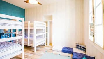 Une chambre avec des lits superposés, un ventilateur de plafond et une fenêtre avec des rideaux.