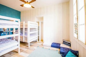 A room with bunk beds, a ceiling fan, and a window with curtains.