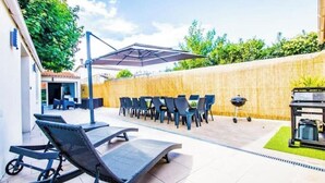An outdoor patio with lounge chairs, a barbecue grill, and a covered seating area. - "Côté sauvage" 4-star vacation rental for 16 people (La Tremblade)