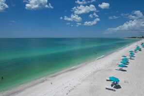 A beach with clear turquoise water, white sand, and a row of blue umbrellas. - Siesta Key 234 - Two Bedroom Apartment, Sleeps 6 (Siesta Key)
