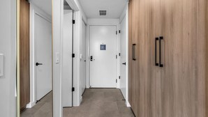 Um corredor com portas brancas, um armário de madeira e um respiradouro no teto.