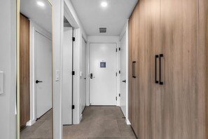Ein Flur mit weißen Türen, einem Holzschrank und einem Deckenventil.