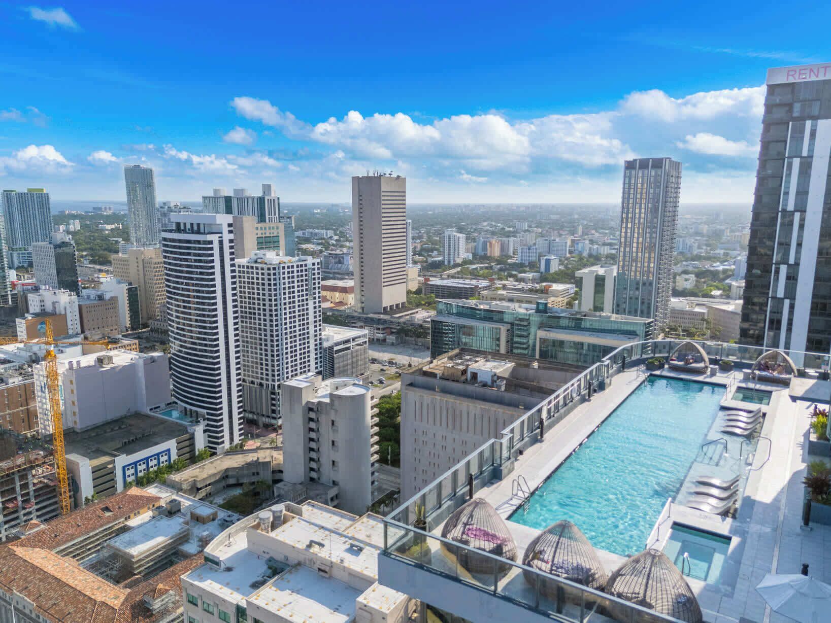 A high-rise building with a rooftop pool and a view of the cityscape.