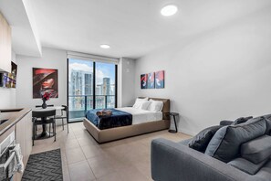 Ein modernes Hotelzimmer mit Bett, Sofa, Schreibtisch und Blick auf die Stadtlandschaft.