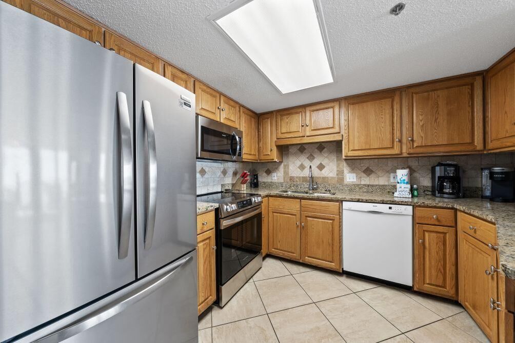 A modern kitchen with stainless steel appliances, wooden cabinets, and a skylight.