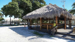 Ein Gebäude mit einem Reetdach und einer Bar, umgeben von einem Zaun und Palmen.
