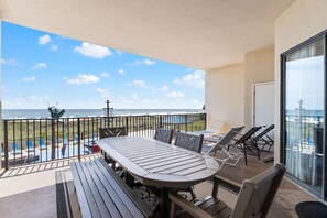 A balcony with a table and chairs, overlooking a pool and the ocean. - Phoenix 5 106 (Orange Beach)